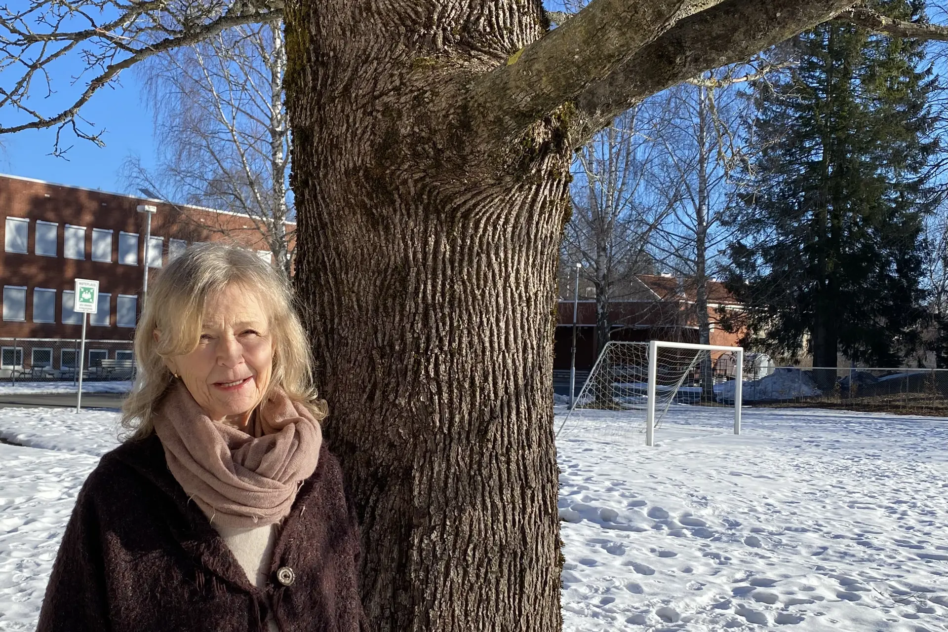 En kvinne som står ved siden av et tre