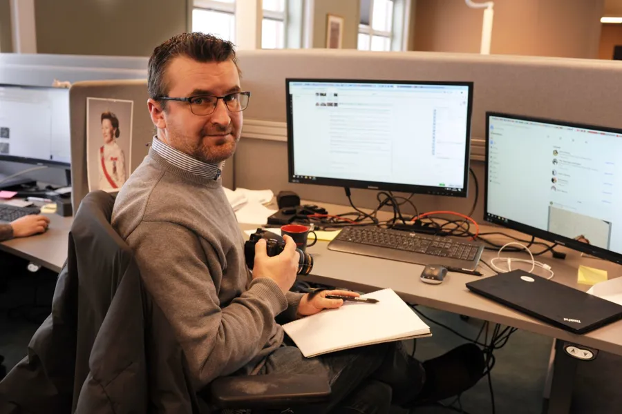 En mann som sitter ved et skrivebord med en datamaskin og en notatbok