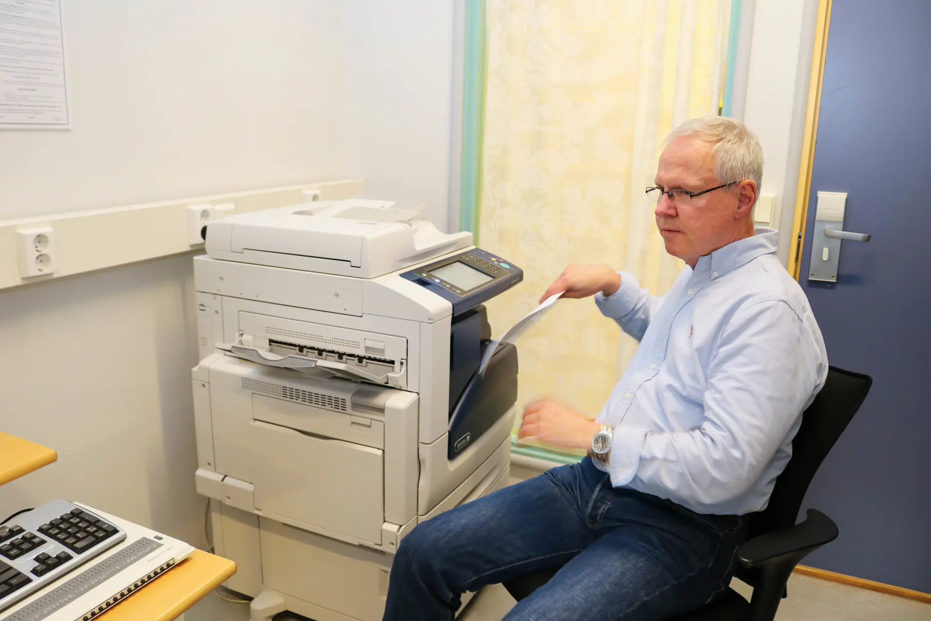 En person som sitter i en stol og betjener en multifunksjonsskriver