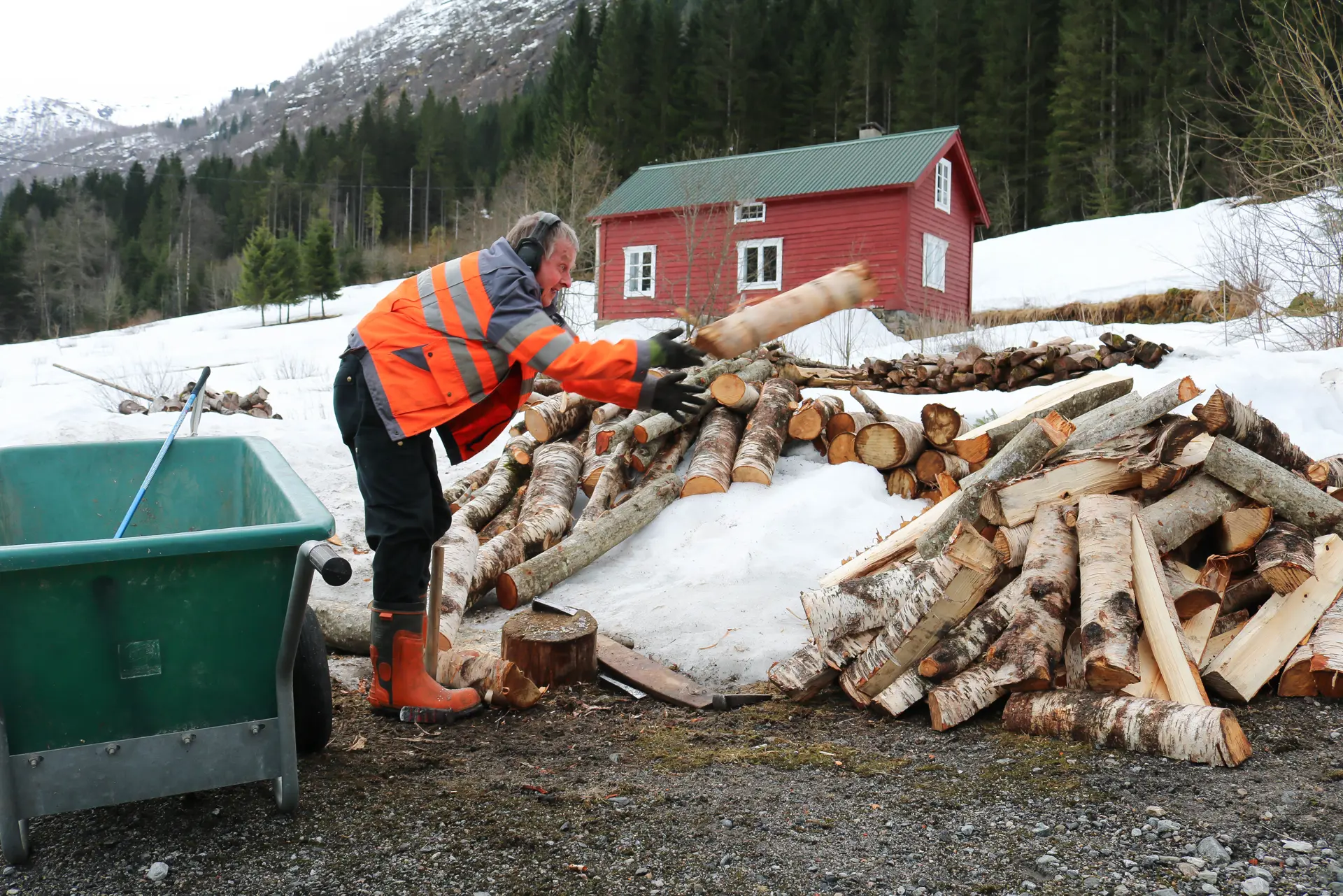Mann som hiver trestokker i en haug